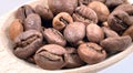Top view of a pile of scattered aromatic roasted brown coffee beans with a wooden scoop. Coffee beans in a wooden spoon