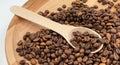 Top view of a pile of scattered aromatic roasted brown coffee beans with a wooden scoop. Coffee beans in a wooden spoon