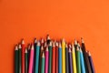 Top view of a pile of sharp colorful pencils isolated on an orange background