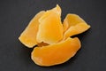 Top view of pile of sliced dehydrated mango on black background.