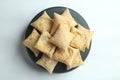 Top view of a pile of square puff biscuits on a black pastry stand