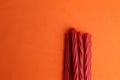 Top view of a pile of sweet red licorice isolated on an orange surface