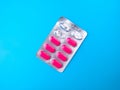 Top view of pink antibiotic pills in gray packaging isolated on a blue background