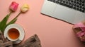 Top view of pink creative workspace with teacup, flowers, laptop and copy space Royalty Free Stock Photo