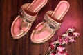 Top view of pink decorative bridal sandals near flowers on a wooden table Royalty Free Stock Photo