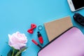 Top view of pink lady bag with diary book, pen, lipstick, bow, ring, car key, smartphone and sweet rose on blue background Royalty Free Stock Photo