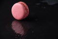 Top view of pink macaron on wet black slate stone, with reflection, horizontal,