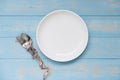 spoon and fork above white dish with pink Measuring tape on blue pastel color wooden table. dieting , weight loss and