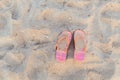 Top view of pink and orange ornamental flip flops at sand on sea beach Royalty Free Stock Photo