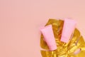 Top view of a pink tube of cream mockup with a golden monstera leaf on a pink background. Unbranded cosmetics package