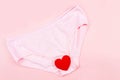 Top view Pink underpants and red heart isolated on pink background. Woman hygiene, Concept of critical days, menstruation,health