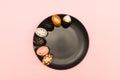 Top view of pink, white and golden decorated eeaster eggs on black plate on pink background. Trendy holiday backdrop