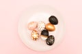 Top view of pink, white and golden decorated eeaster eggs on pink plate on pink background. Trendy holiday backdrop