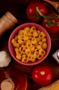 top view of pipe-rigate pasta in bowl with salt tomato butter on wooden background