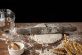 Top view of pizza dough with rolling pin, on wooden table with flour, jug of water, salt and wheat, selective focus, black backgro Royalty Free Stock Photo