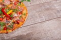 Top view of pizza on a shabby table background, close-up. A half of meat pizza with vegetables and spicy seasoning. Copy