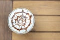 Top view of plastic cup of iced capuchino with chocolate sauce art pattern on wooden table Royalty Free Stock Photo