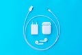 Top view plastic white wireless headphones for smartphone, charging case, Lighning USB, adapter on a pastel blue background. Copy Royalty Free Stock Photo