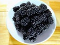 Top view of a plate of blackberries on a wooden surface