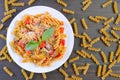 Top View of a Plate of Fusilli Pasta in Tomato Sauce with Dried Pastas Scattered Around