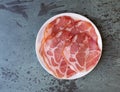 Top view of a plate of dry coppa on a gray mottled tabletop