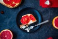 Top view plate with piece of baked cheesecake with red grapefruit slices and vintage fork on the black stone background with ingre Royalty Free Stock Photo
