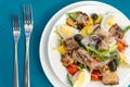 Top view of a plate of Salade nicoise on blue table