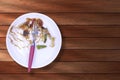 Top view of plate of spicy pasta eaten with fork on wooden table background. top view