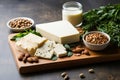 Top view of a plate of spinach, beans,Tofu, lentils, nuts, soy milk, spinach and are displayed on a stone background.