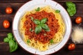 Top view of a plate of steaming Spaghetti Bolognese garnished with fresh basil leaves and grated Parmesan cheese