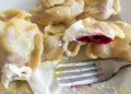 Plate with traditional Ukrainian desert vareniky stuffed with cherry berry and topped with sour cream