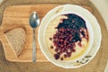 Top view of a plate of wheat porridge for a healthy gluten-free breakfast, next to a spoon and a piece of bread. A plate