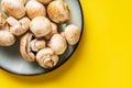 Top view on plate with white common champignon mushrooms on yellow background Royalty Free Stock Photo