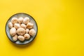 Top view on plate with white common champignon mushrooms on yellow background Royalty Free Stock Photo
