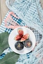 Top view of a plate of whole and sliced black figs, a leaf and blue and pink tablecloths on a wooden table