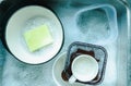 Top view of plates and crockery, coffee mugs in the sink employing dishes with sponge and bubbles of dishwashing liquid, washing Royalty Free Stock Photo