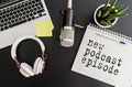 Top view of podcast recording equipment on desk with words new podcast episode written on note pad