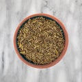 Top view of a portion of organic thyme leaf on a small bowl atop a marble countertop