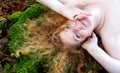 Top view portrait of a beautiful sexy lovely mature redhead woman with red curly hair lying on green moss trunk in the forest Royalty Free Stock Photo