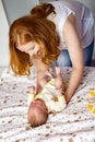 Top view portrait cute newborn redhead baby in childish overalls lying crib during mother dressing