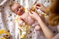 Top view portrait cute newborn redhead baby in childish overalls lying crib during mother dressing