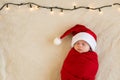 Top View Portrait First Days Life Newborn Cute Funny Sleeping Baby In Santa Hat Wrapped In Red Diaper At White Garland Royalty Free Stock Photo