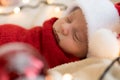 Top View Portrait First Days Of Life Newborn Cute Funny Sleeping Child Baby In Santa Hat Wrapped In Red Diaper At White