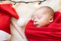 Top View Portrait First Days Of Life Newborn Cute Sleeping Baby In Santa Hat Wrapped In Red Diaper rug At White Garland Royalty Free Stock Photo