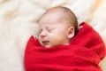 Top View Portrait First Days Of Life Newborn Cute Sleeping Baby In Santa Hat Wrapped In Red Diaper rug At White Garland