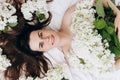 Top view portrait of smiling millennial young woman sincere happy looking at camera laying in cozy white bed, beautiful flowers Royalty Free Stock Photo