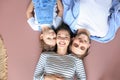 Top view portrait of smiling young parents with little preschooler daughter lying relaxing on warm floor at home