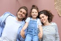 Top view portrait of smiling young parents with little preschooler daughter lying relaxing on warm floor