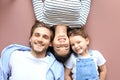 Top view portrait of smiling young parents with little preschooler daughter lying relaxing on warm floor at home