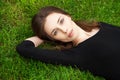 Top view portrait of a young beautiful woman in black dress lies on green lawn in a park Royalty Free Stock Photo